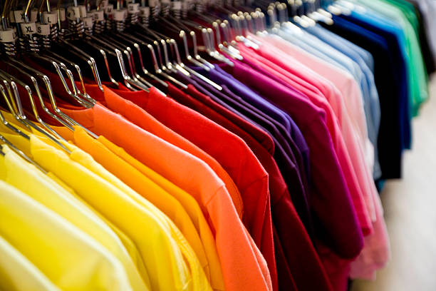 A row of colorful t-shirts hanging on a rack.Our images are processed from